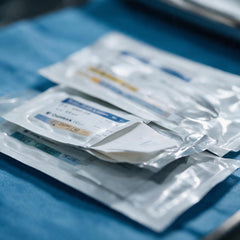 Sterile Nahtmaterial-Peelbeutel auf blauem Abdecktuch – chirurgisches Nahtmaterial bei SurgicMate